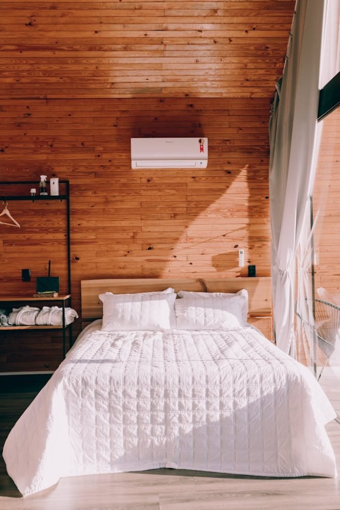 Charming cabin bedroom featuring wooden walls and sunlight streaming in.